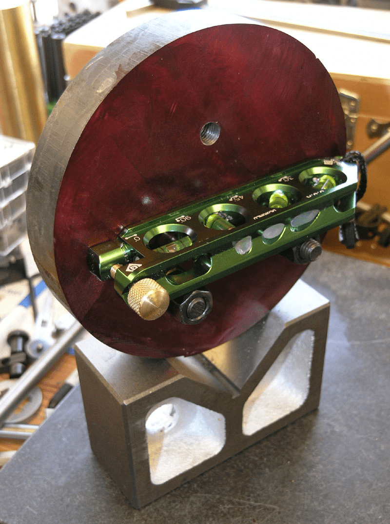 Round red metal object with green tool attached.