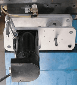 Black cylindrical component with white plate and various holes.