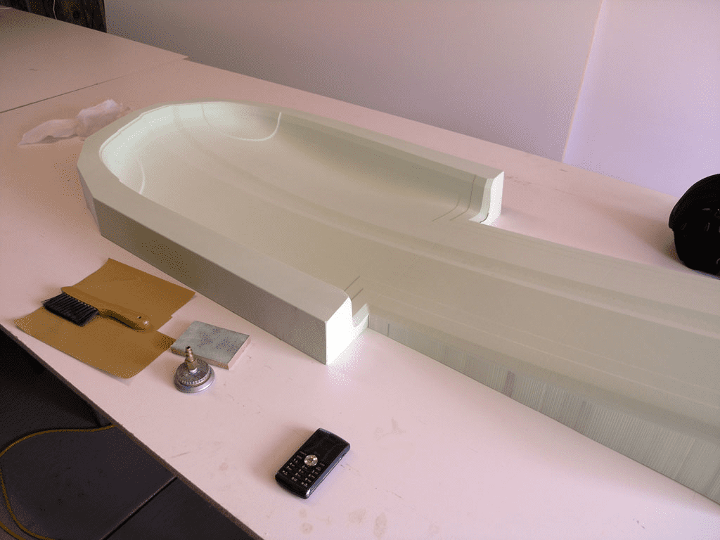 A large, white, curved workbench with tools and materials, including a hammer, screwdriver, pliers, wrenches, and wood shavings.