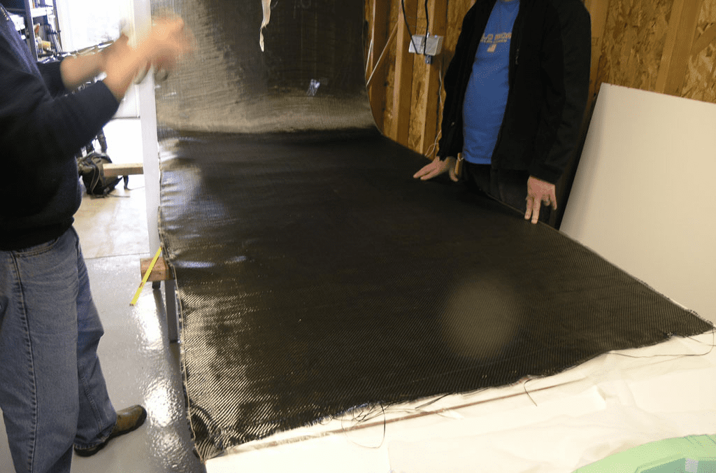 Two men standing in front of a textured black material on a white surface.