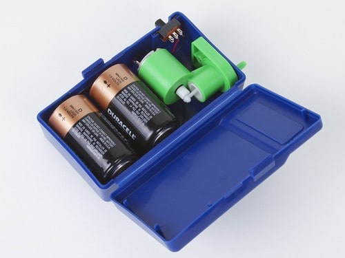 Blue plastic case with two batteries and green object inside.