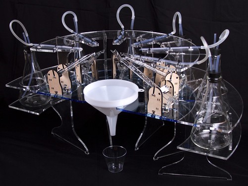 Clear curved acrylic or plastic structure with funnel on black background.