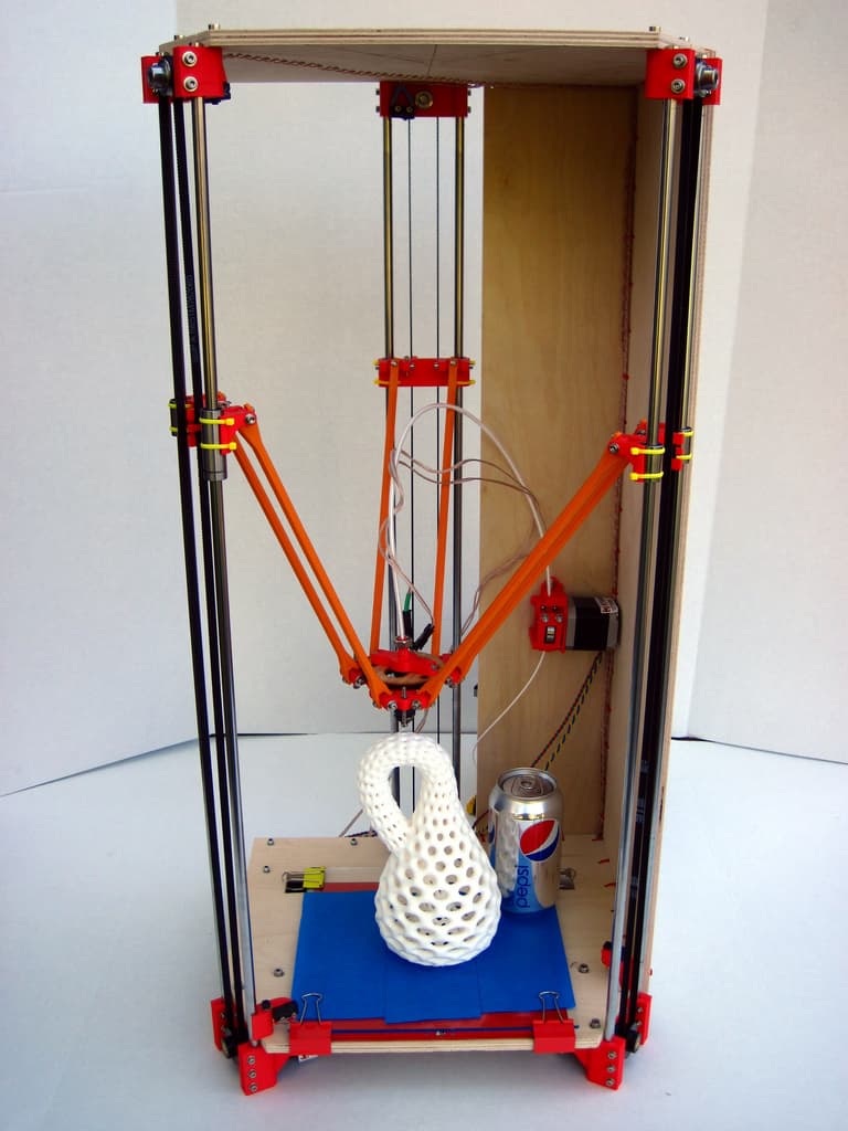 A Rostock Max v2 3D printer with wooden frame and orange accents.