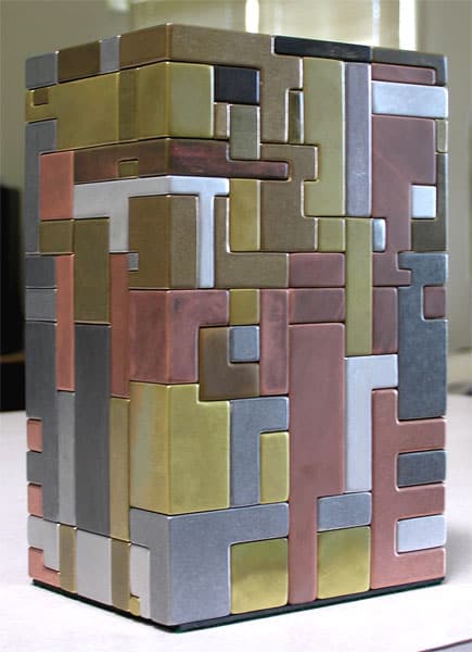 Colored metallic puzzle cube made up of interlocking blocks on a white office background.