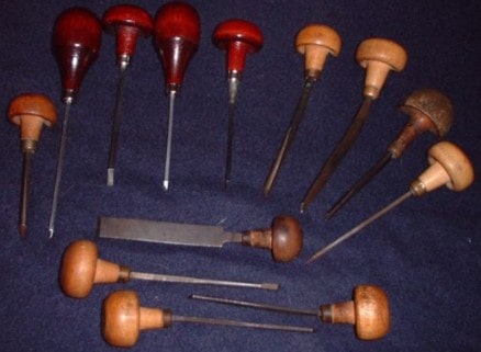 Graver tools with wooden handles and metal tips on a gray background.