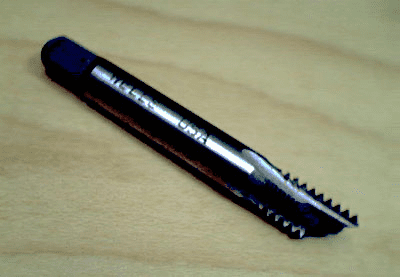 Black drill bit or tap with serrated edge.