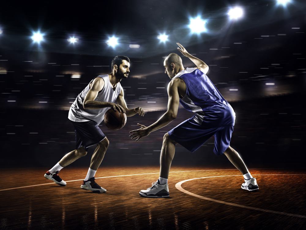 Two men playing basketball indoors.
