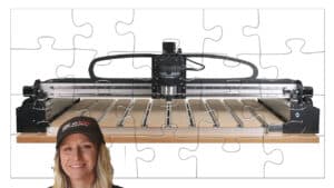 A woman in a black cap stands next to a laser cutter with a flat table and components attached, against a white background.