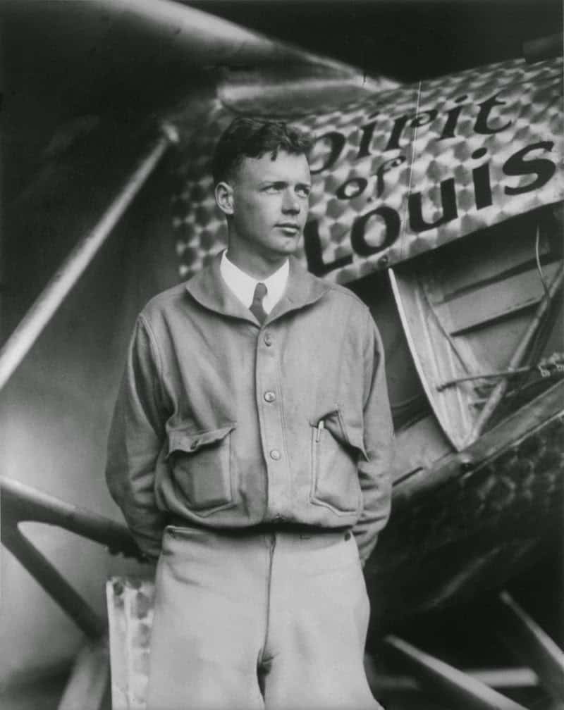 Charles Lindbergh standing in front of the Spirit of St. Louis aircraft.