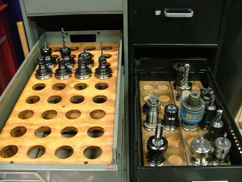 Collection of various tool holders in a storage cabinet with wooden boards.