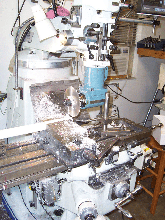 Cluttered white mill with metal shavings and debris on its surface.