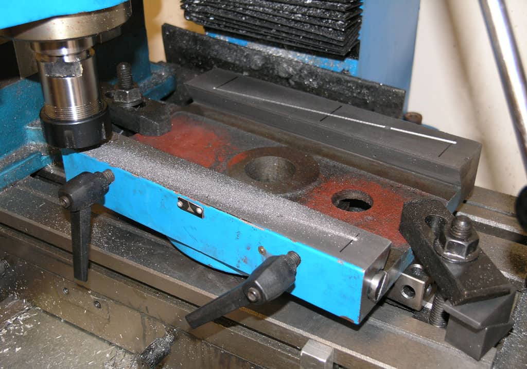 Milling machine vice with blue frame, black components, and red rust.