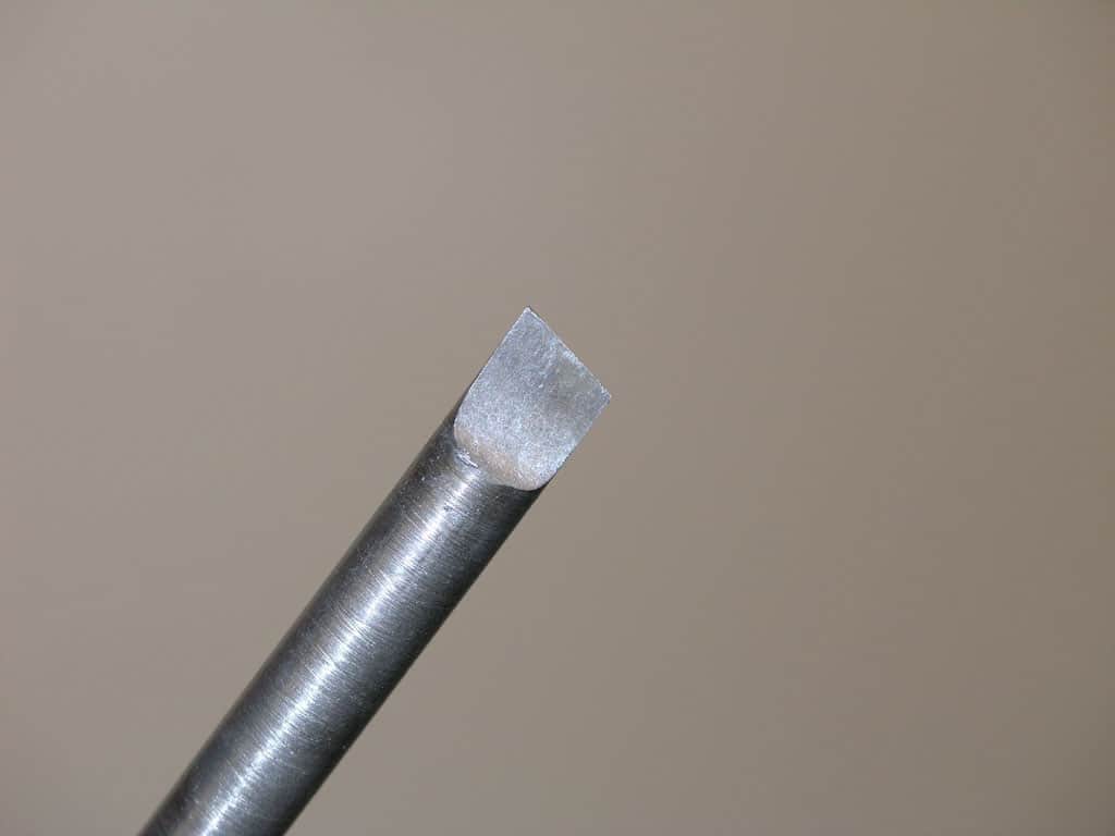 Metal tool with square-shaped tip, shiny surface, likely used for cutting metal.