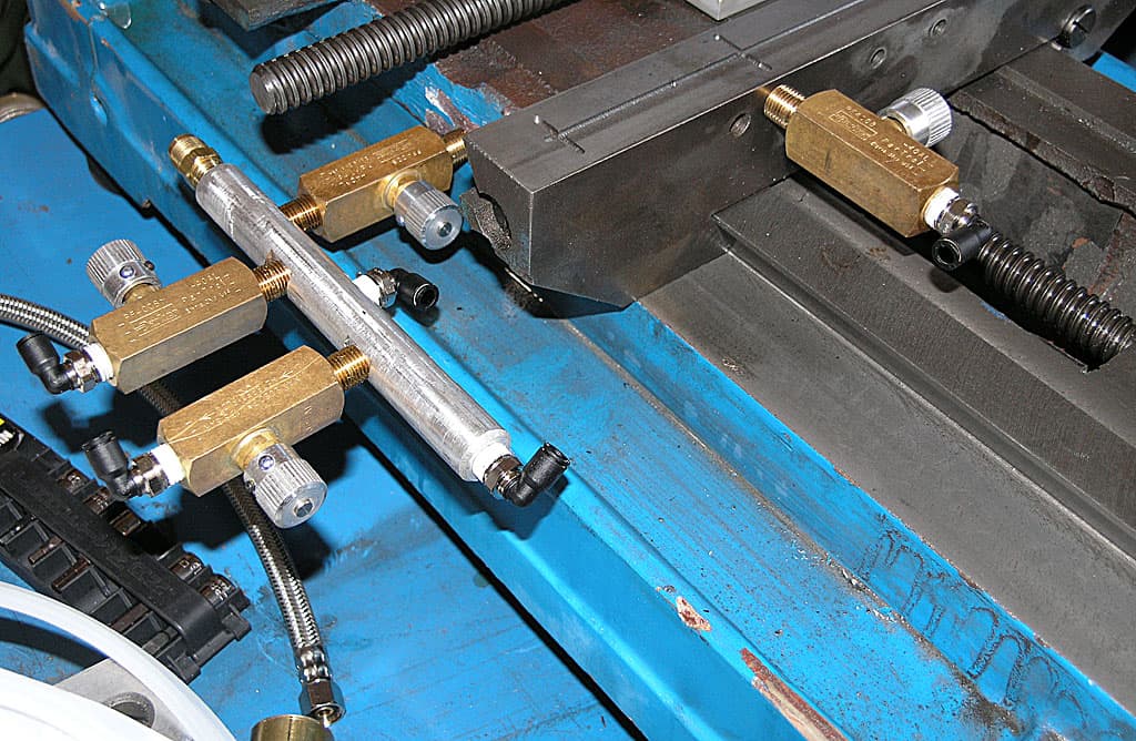 Precision mechanical components on a bright blue metal surface in a machine shop or fabrication facility.