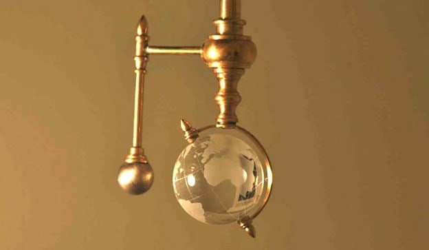 Brass armature with clear glass globe suspended from ornate hook.