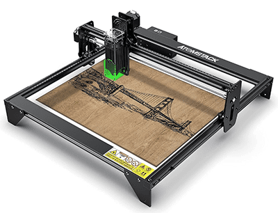 A black and silver laser engraver with ATOMSTACK branding and a small green beam emitting from the top.