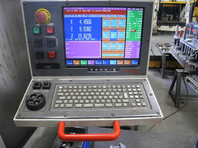 A computer screen showing a CNC machine control panel with buttons, knobs, and keyboard.
