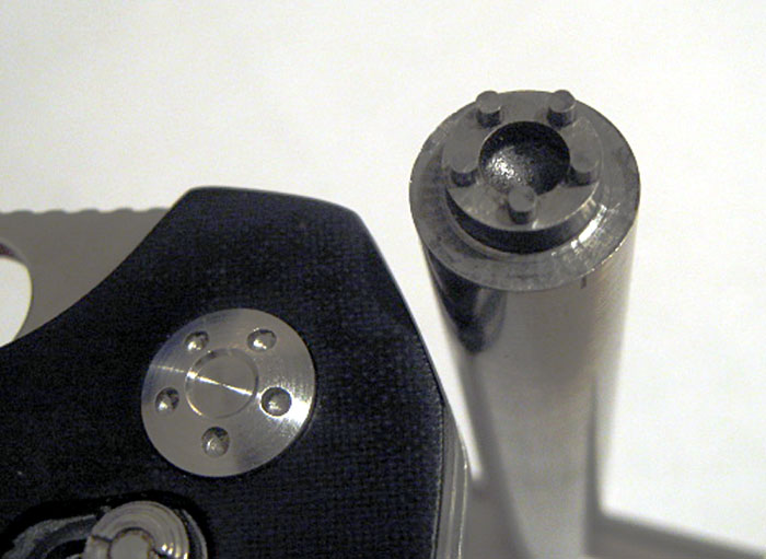 Black hexagon with silver circular plate and three small holes.