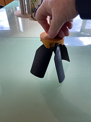 Hand holding a scrapera or blade tool in a machining context.