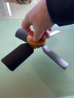 Hand holding a tool with three flat surfaces and a rounded handle.