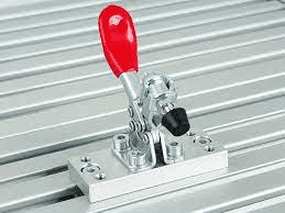Silver metal tool on slatted metal surface with red handle and black knob.