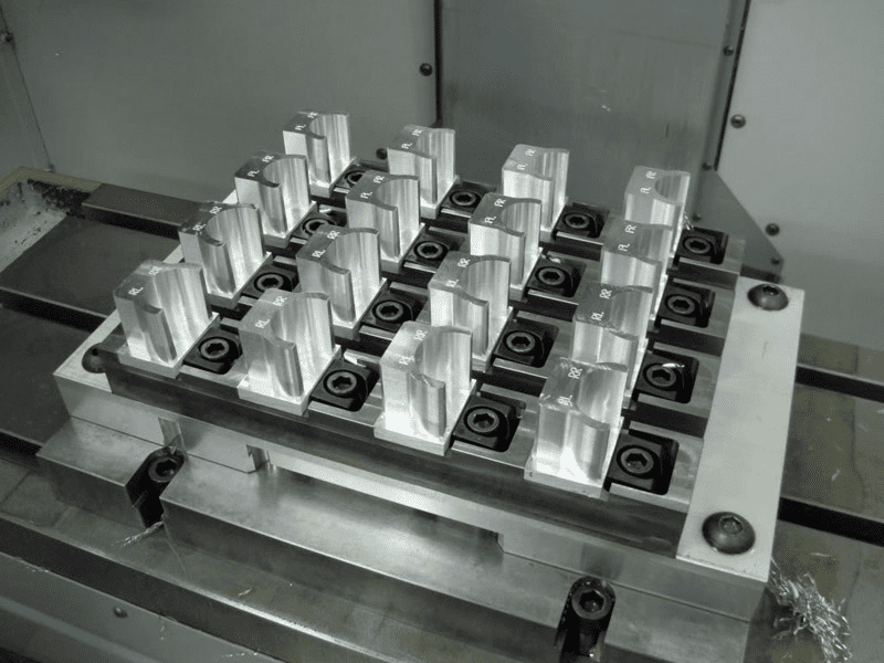 Metal tooling setup with silver blocks on a metal base featuring black components and knobs.