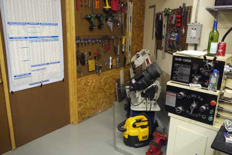 Well-equipped metal fabrication workshop with drill press, vise, and measuring devices.