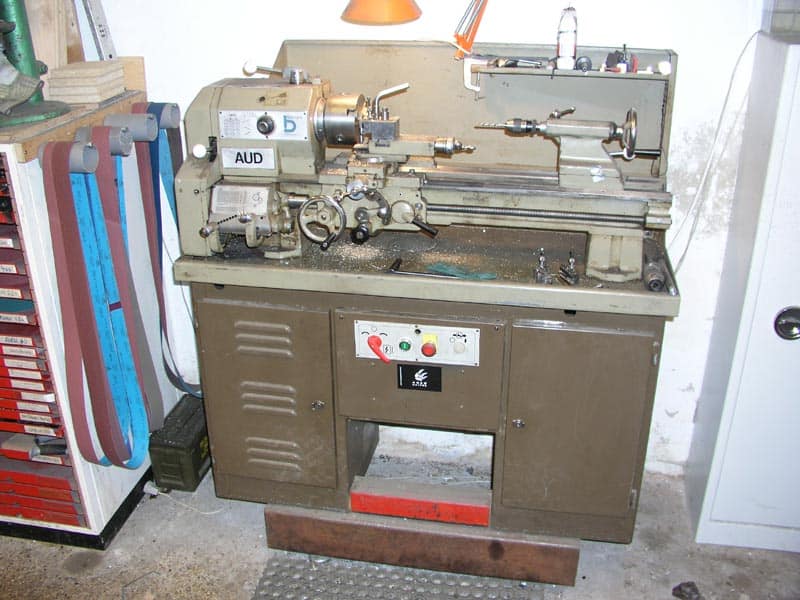 Large gray lathe with "AUD" label and red switch in a workshop or garage.