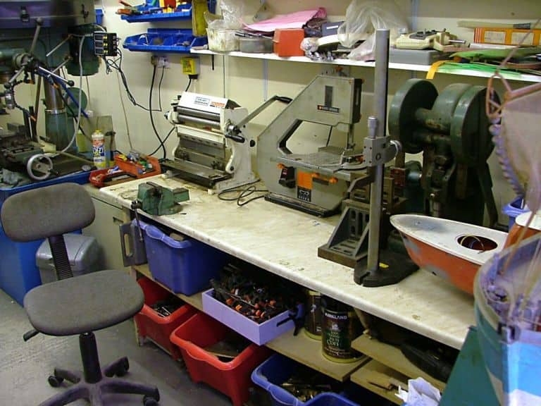 Cluttered workshop with drill press, bandsaw, and vise.