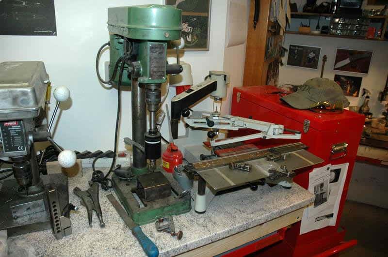 Industrial equipment on a gray table, including drill press and milling machine.