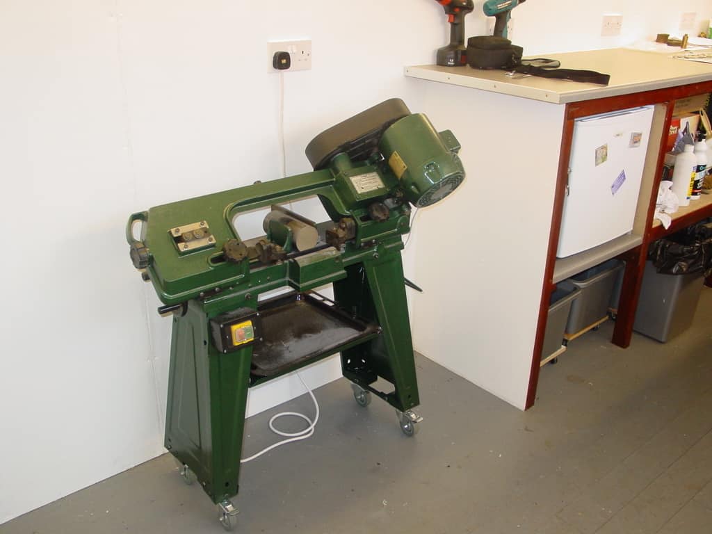 Green metalworking machine with wheels, milling or lathe equipment on a flat top surface.