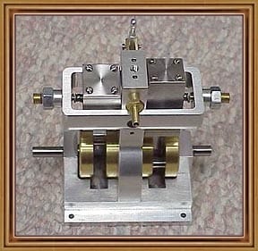 Silver metal device with brass components and central mechanism on mottled background.