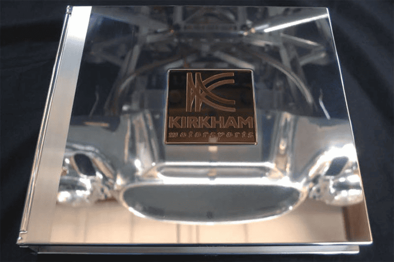 Glass award with engraved Kirkham Motorsports logo on dark background.