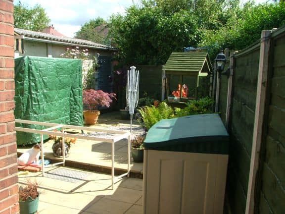 Compact outdoor workshop with tools and equipment in a covered area surrounded by greenery.