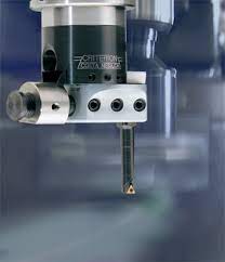 Close-up of a drill bit with a cylindrical body and three holes.