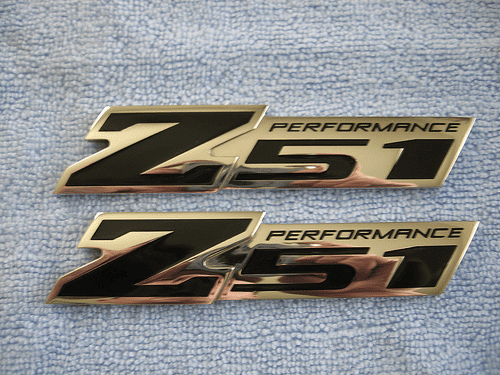 Metallic emblem with "Z51 PERFORMANCE" text and light blue fabric background.