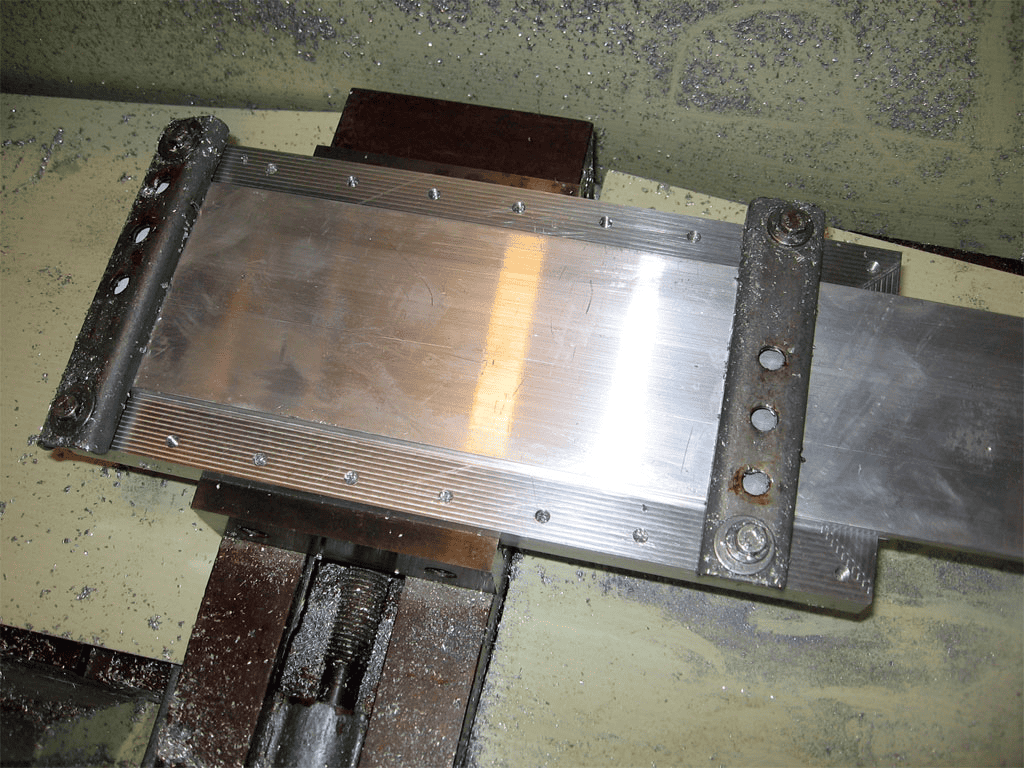 A large metal plate secured by bolts on another metal component in a workshop setting.
