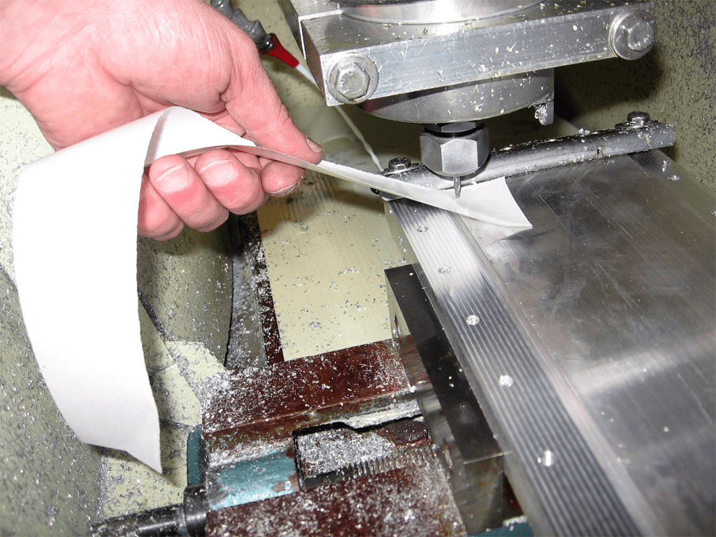 Hand holding material in front of metal machine.