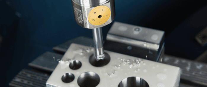 A drill press or milling machine spindle with a yellow protective sleeve and metal shavings.