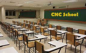 A classroom with rows of empty desks and chairs facing a green chalkboard with "CNC School" written in yellow.