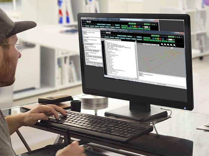 Person working intently on computer with multiple monitors displaying various windows and spreadsheets.