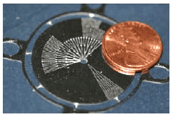 Copper penny on black circular tool with white markings on gray background.