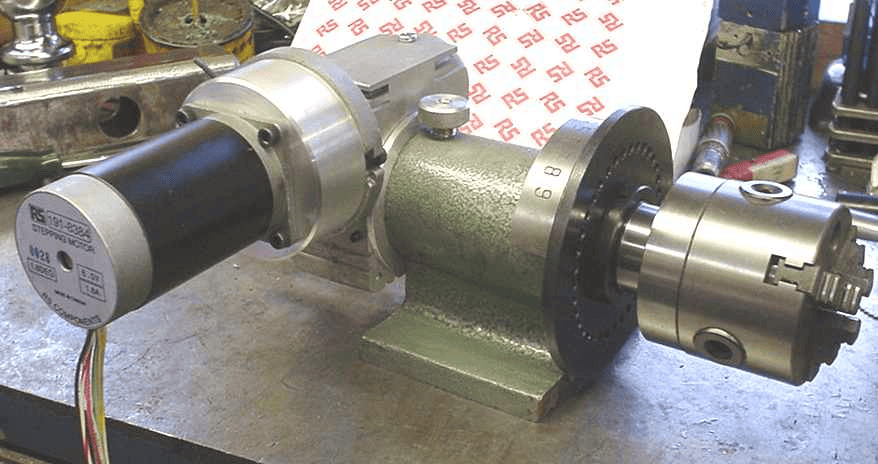 Industrial electric motor with gearhead on workbench in a workshop setting.