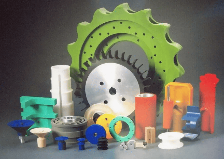 Various plastic and metal parts including gears, pulleys, spindles, bushings, and bearings in a visually appealing arrangement.