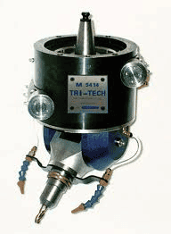 Cylindrical metal object with circular dials and cone-shaped top, labeled M 3436 TRI-TECH.