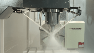 Water jet nozzle on a machine with KOMA branding and industrial surroundings