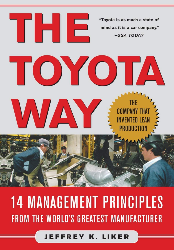 Toyota Way book cover featuring red and gray color scheme, bold typography, company logo, gold seal, assembly line photo.